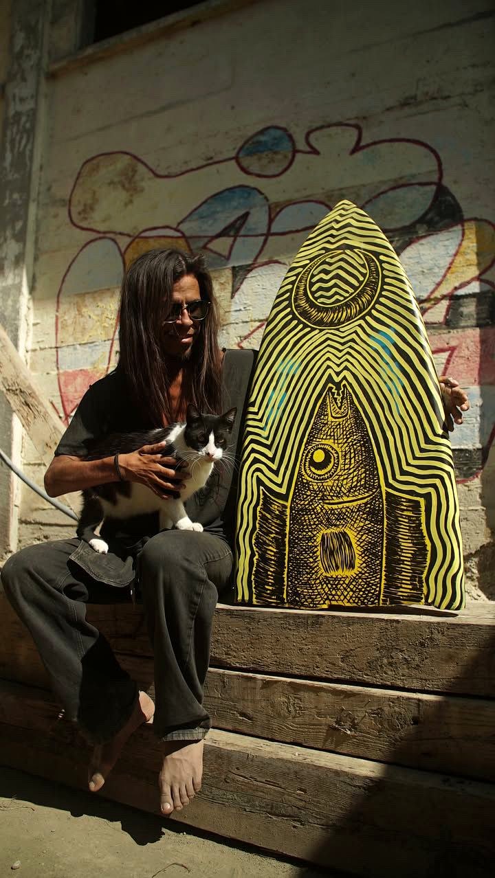 Inti with his cat and a painted surfboard in Lobitos